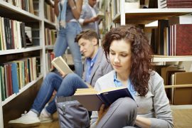 Students reading books in library on floor